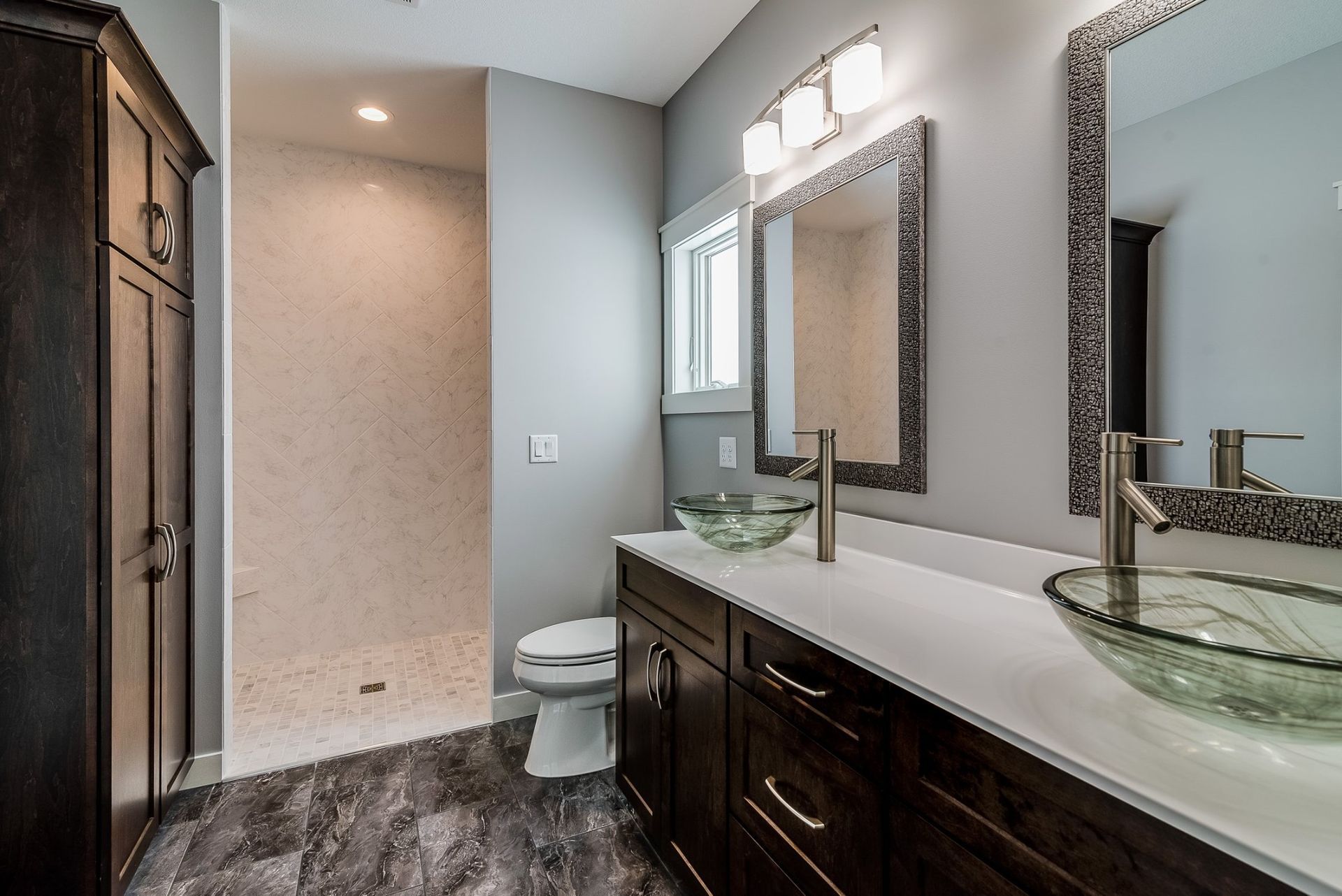 A bathroom with two sinks, a toilet and a walk in shower.