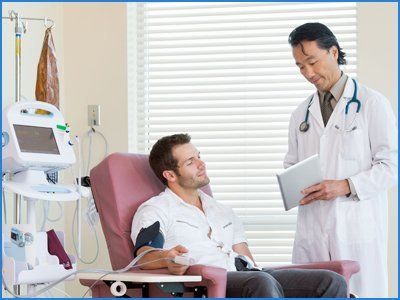 Doctor showing digital tablet to patient in chemo room