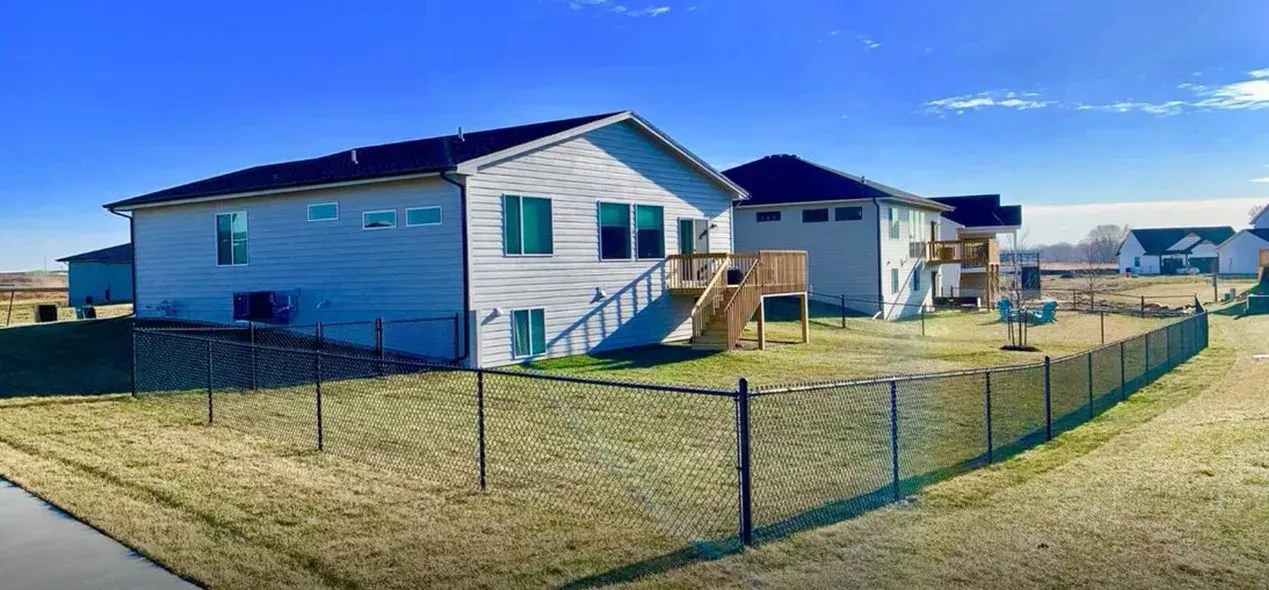 Backyards of houses with fences, clear blue sky.