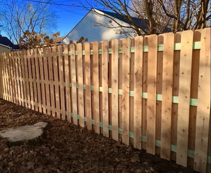 Wooden picket fence in a yard, with visible support beams.