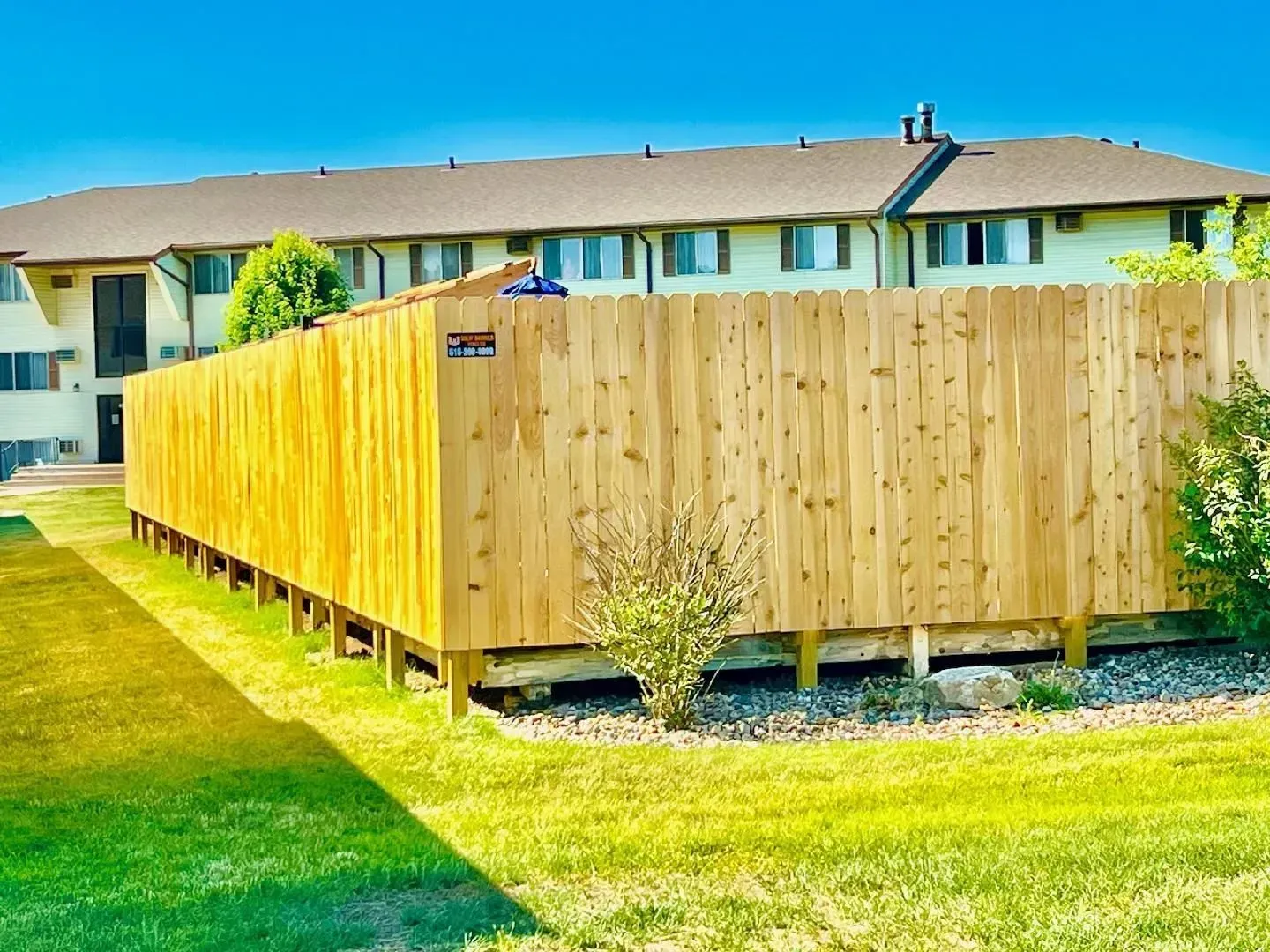 Wooden fence surrounding a building on a grassy lawn.