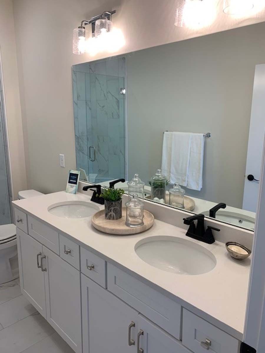 White bathroom vanity with two sinks, mirror, and decor.
