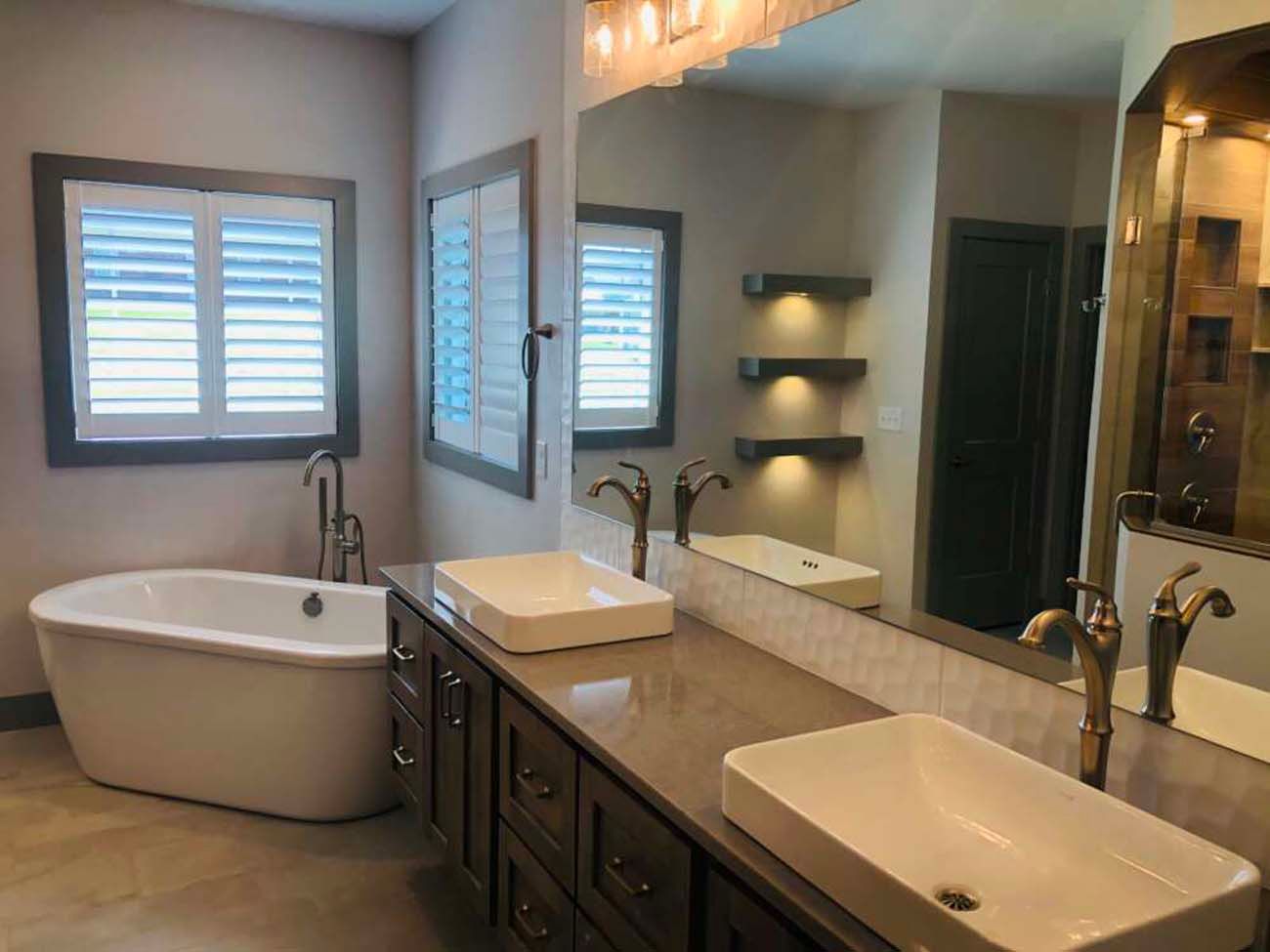 Spacious bathroom with soaking tub, double vanity, and shuttered windows.