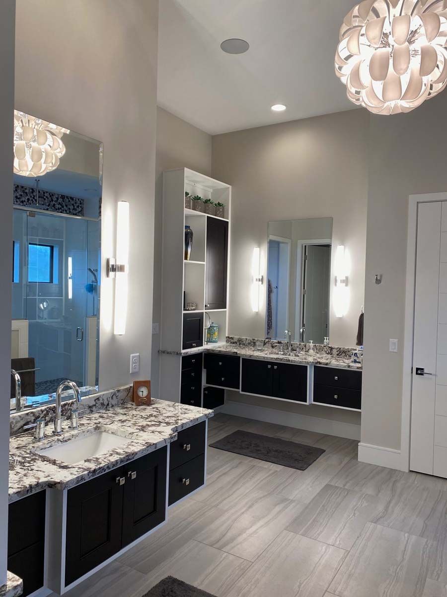 Modern bathroom with double vanity, black cabinets, granite countertops, and light gray walls.
