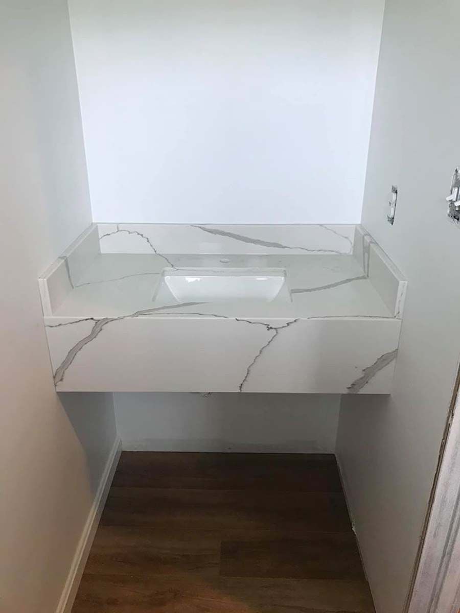 White countertop with marble veining, built-in sink, installed in a narrow bathroom.