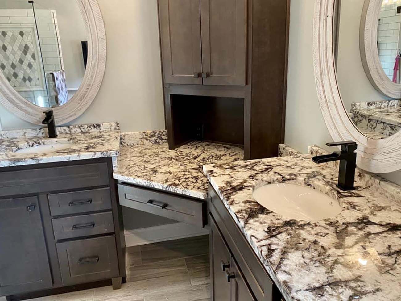 Bathroom with two vanities, oval mirrors, granite countertops, and dark cabinets.
