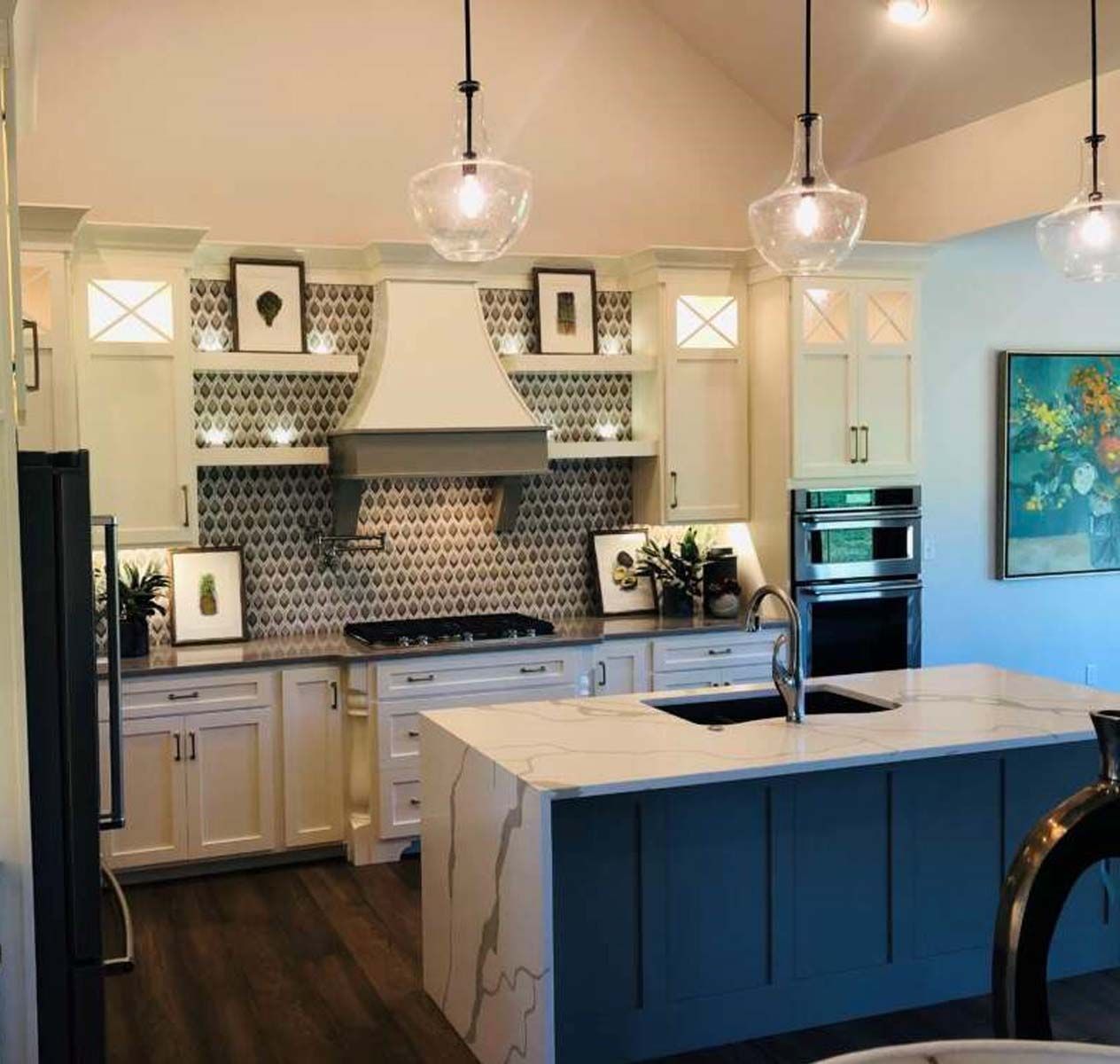 Kitchen with white cabinets, blue island, and patterned backsplash.