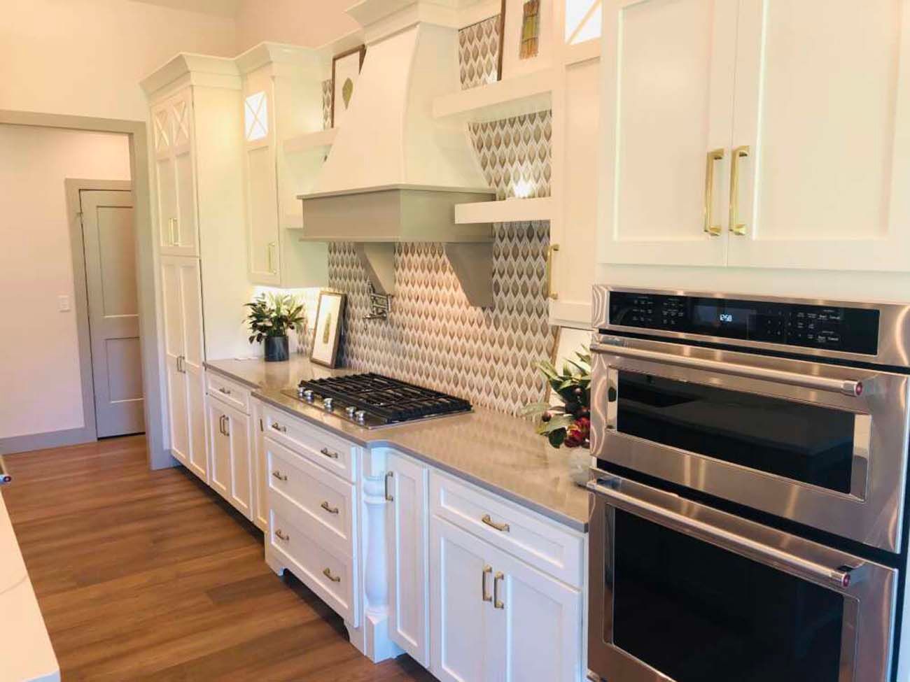 White kitchen with stainless steel appliances, grey countertops, and hardwood floors.
