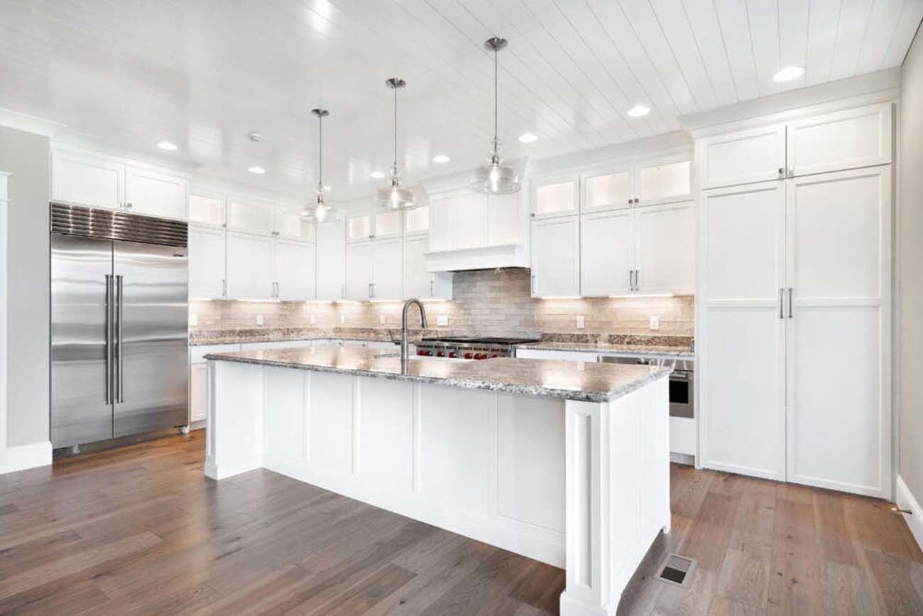 White kitchen with island, stainless steel appliances, and wood flooring.