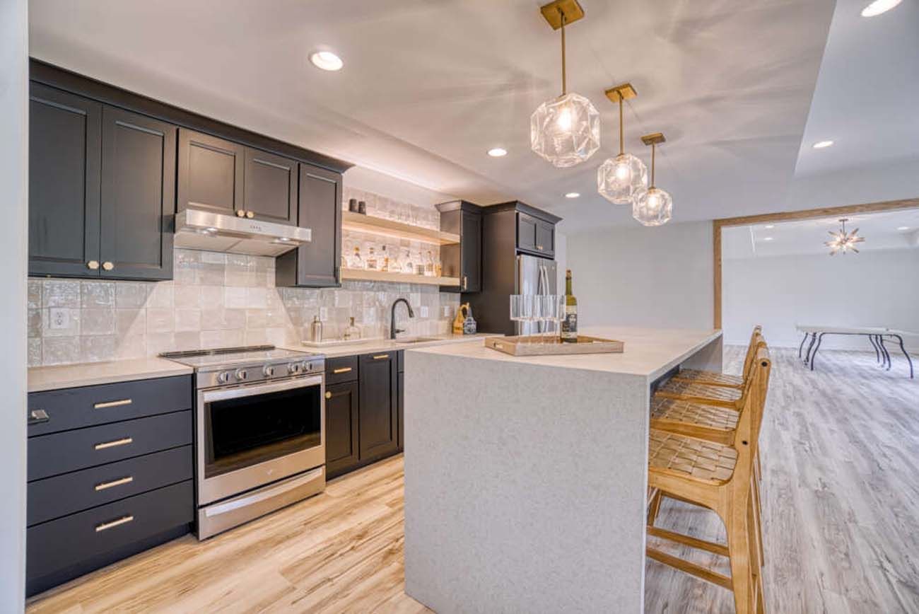 Modern kitchen with dark cabinets, white countertops, and bar seating.