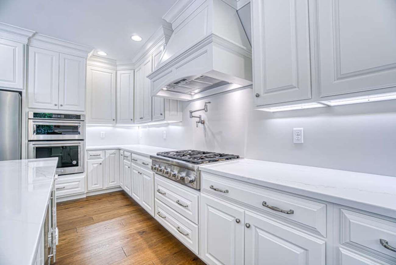 White kitchen with light cabinets, countertops, and stainless steel appliances.