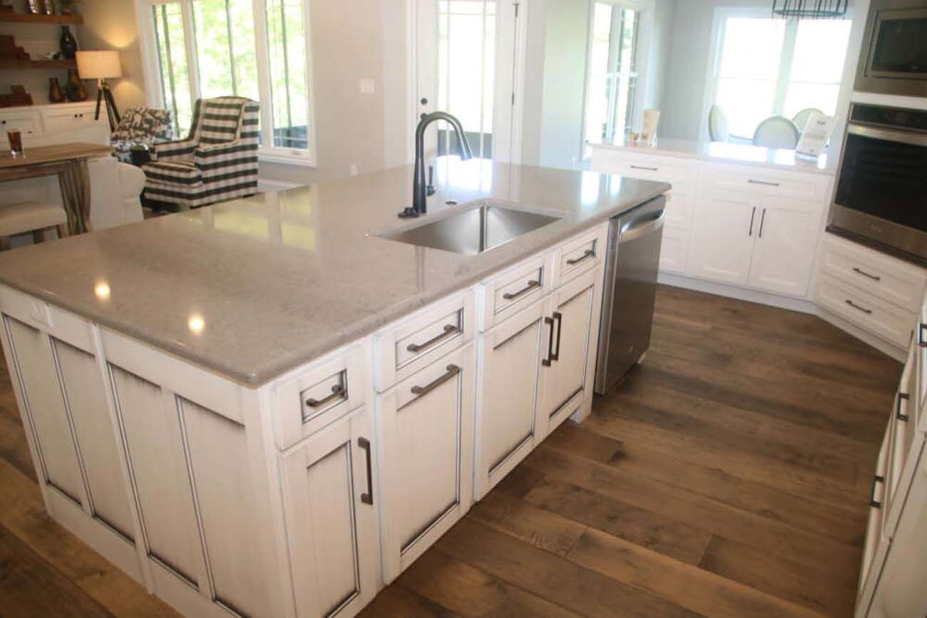 White kitchen island with a sink and dishwasher on a hardwood floor.