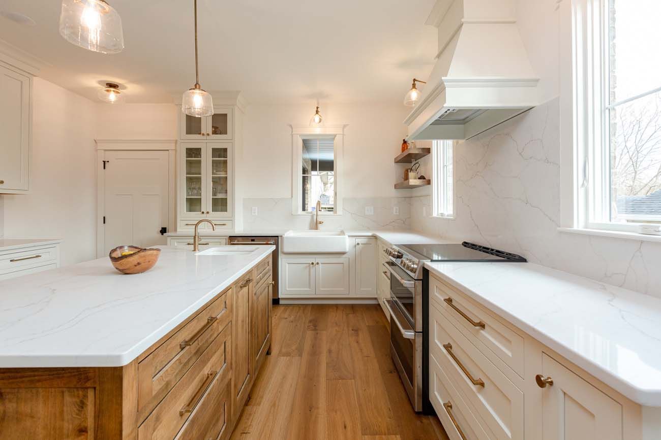 Bright, white kitchen with wooden island, stainless steel appliances, and wood flooring.