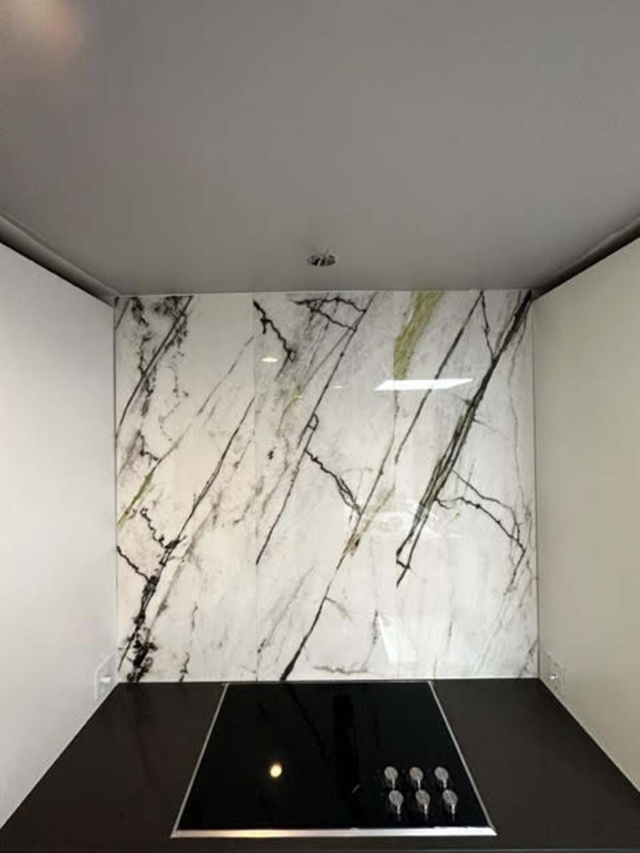 Kitchen with marble backsplash behind a black stovetop. White walls.
