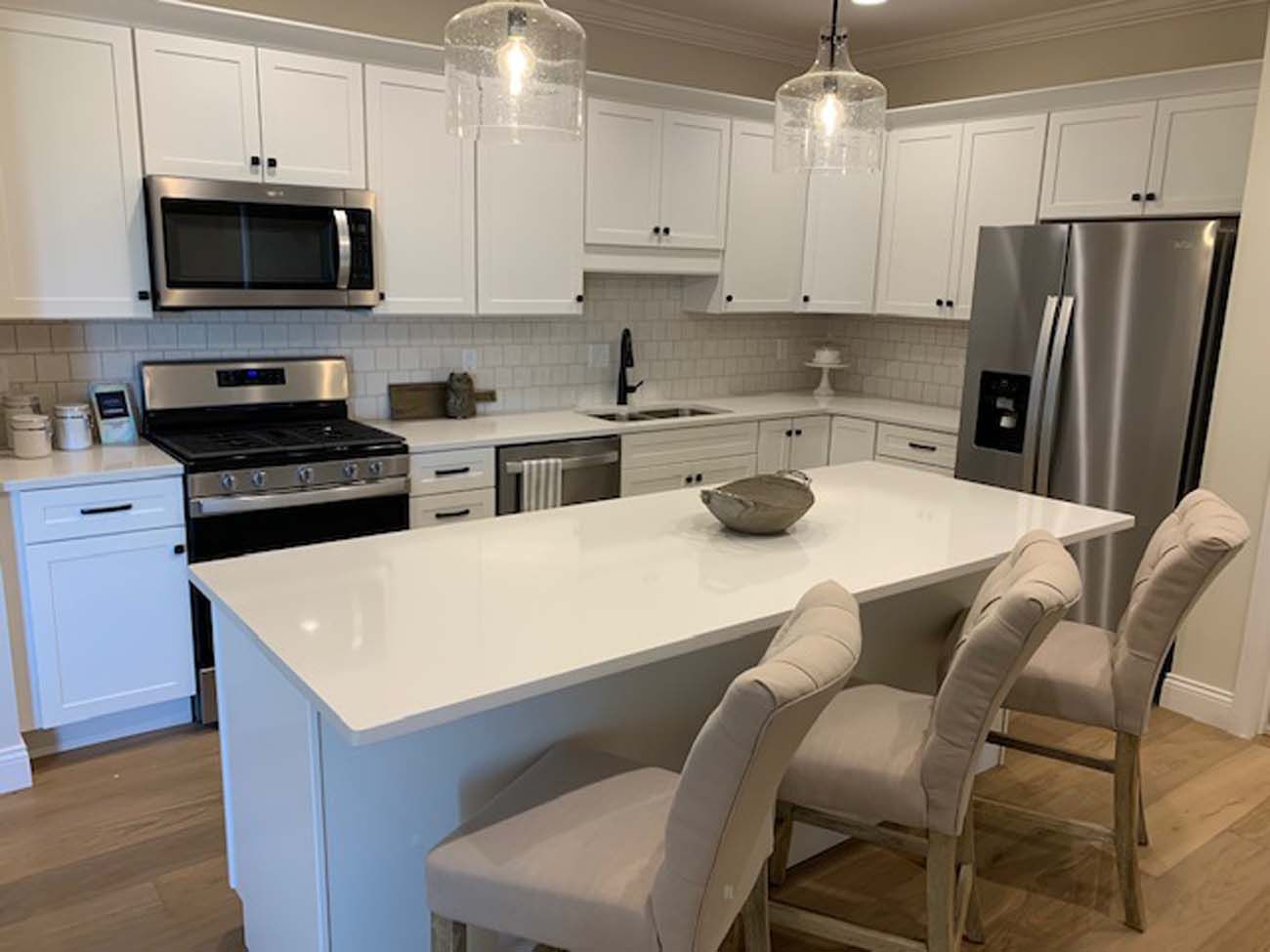 White kitchen with stainless steel appliances, white cabinets, and a kitchen island with seating.