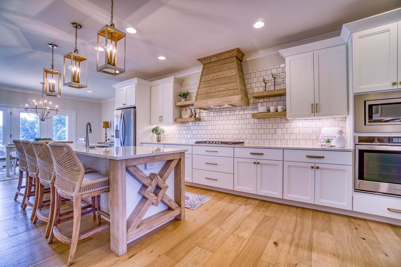 Bright kitchen with white cabinets, wooden accents, and a large island with rattan chairs.