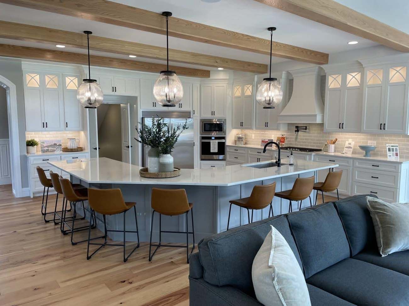 Modern kitchen with large island, light cabinets, wood beams, pendant lights, and bar seating.