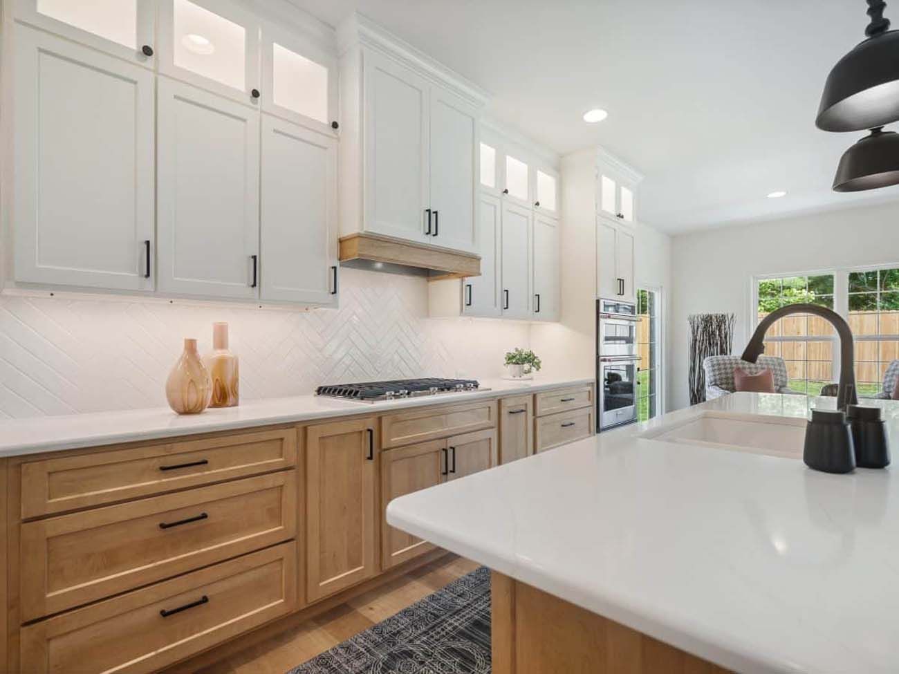 Modern kitchen with white and wood cabinets, white countertops, and black hardware.