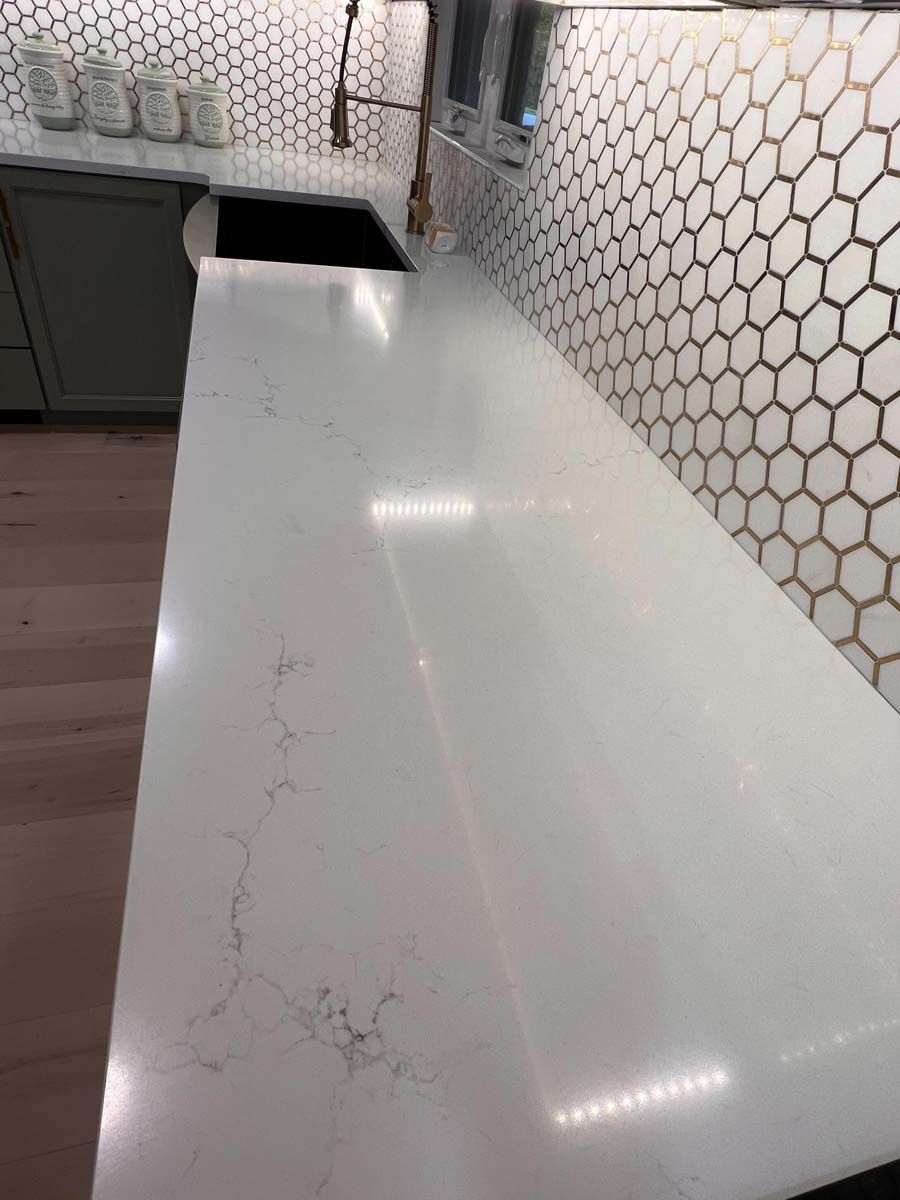 White countertop with subtle veining against hexagon tile backsplash.