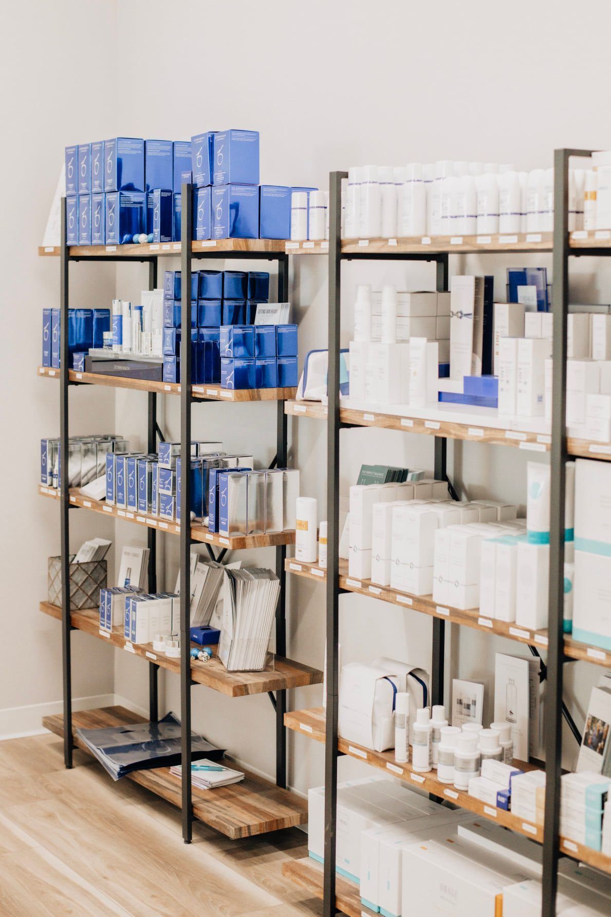 Shelves stocked with skincare products, mostly white and blue packaging, in a well-lit retail setting.