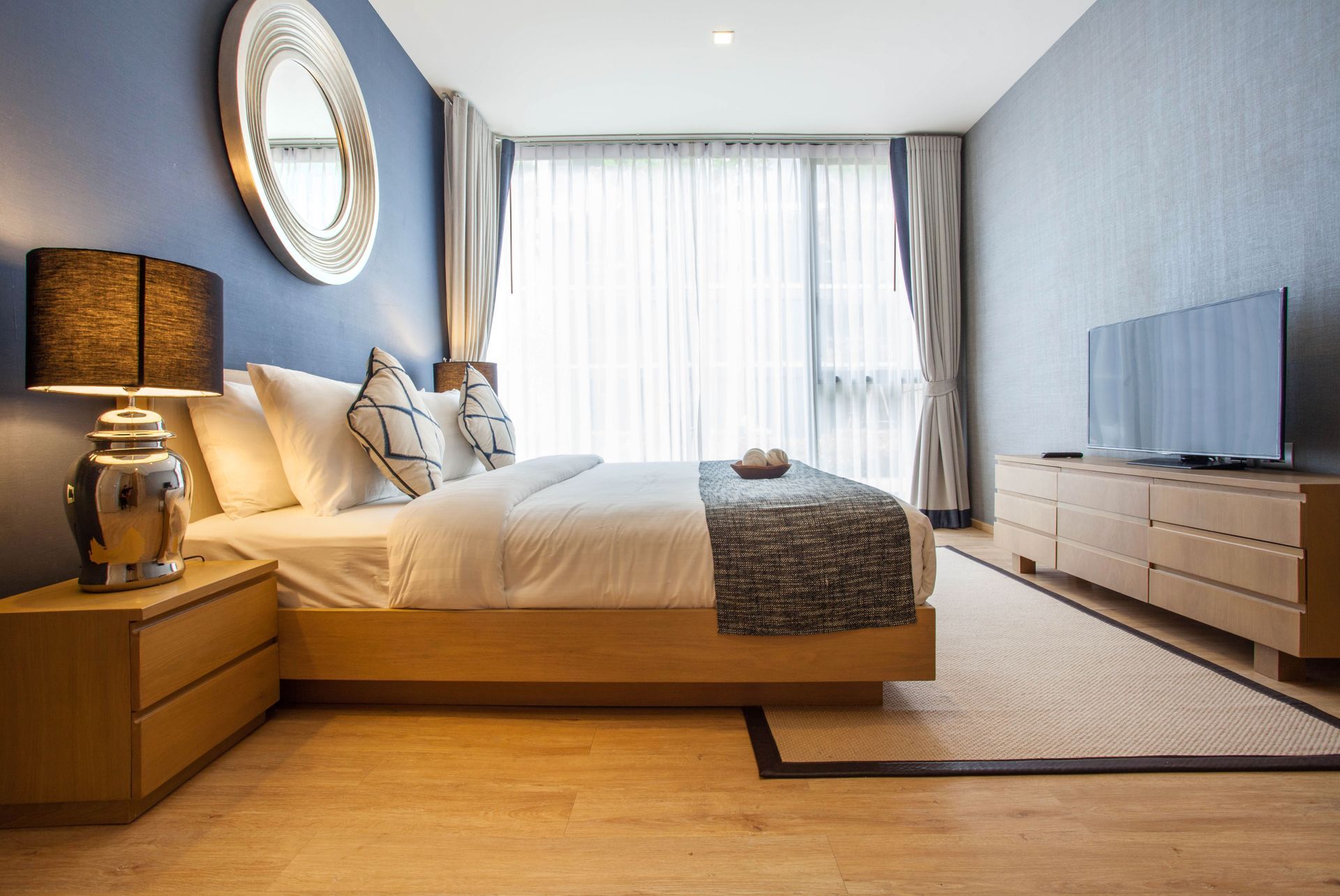 A bedroom with a bed , dresser , nightstand and television.
