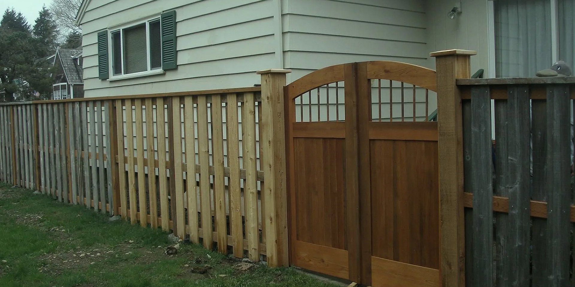 Wooden fence with a gate in front of a house.