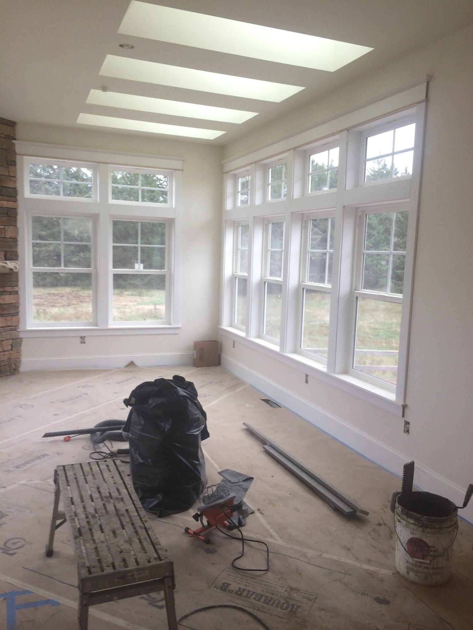 Interior room with white windows, a skylight, and construction debris.