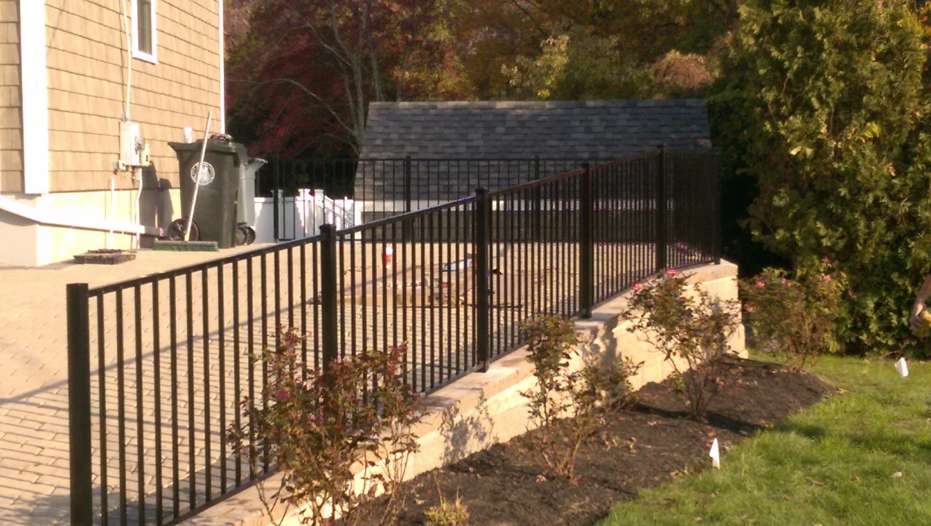 A black wrought iron fence surrounds a patio area in front of a house.