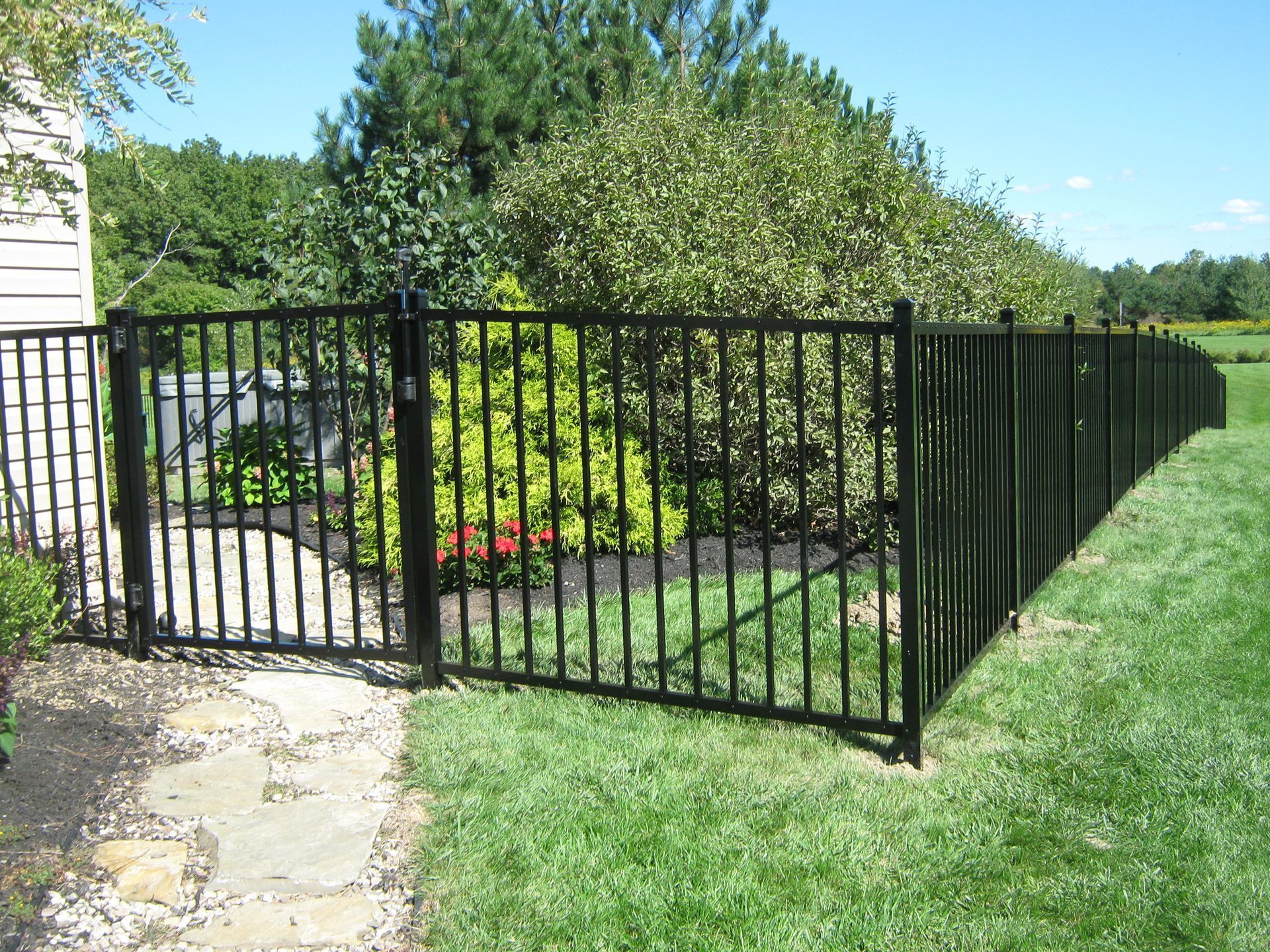 A black metal fence surrounds a lush green yard.