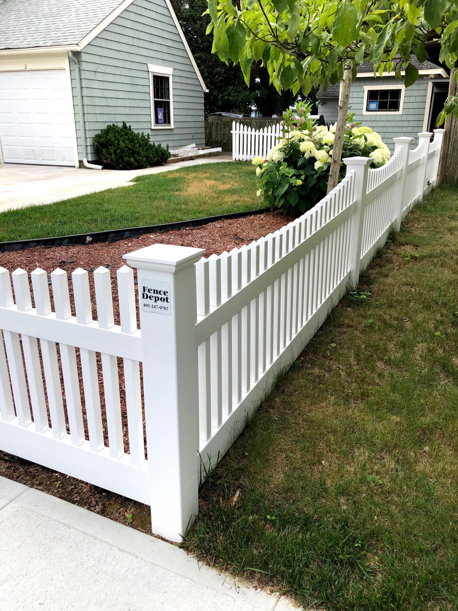 A white picket fence is in front of a house.