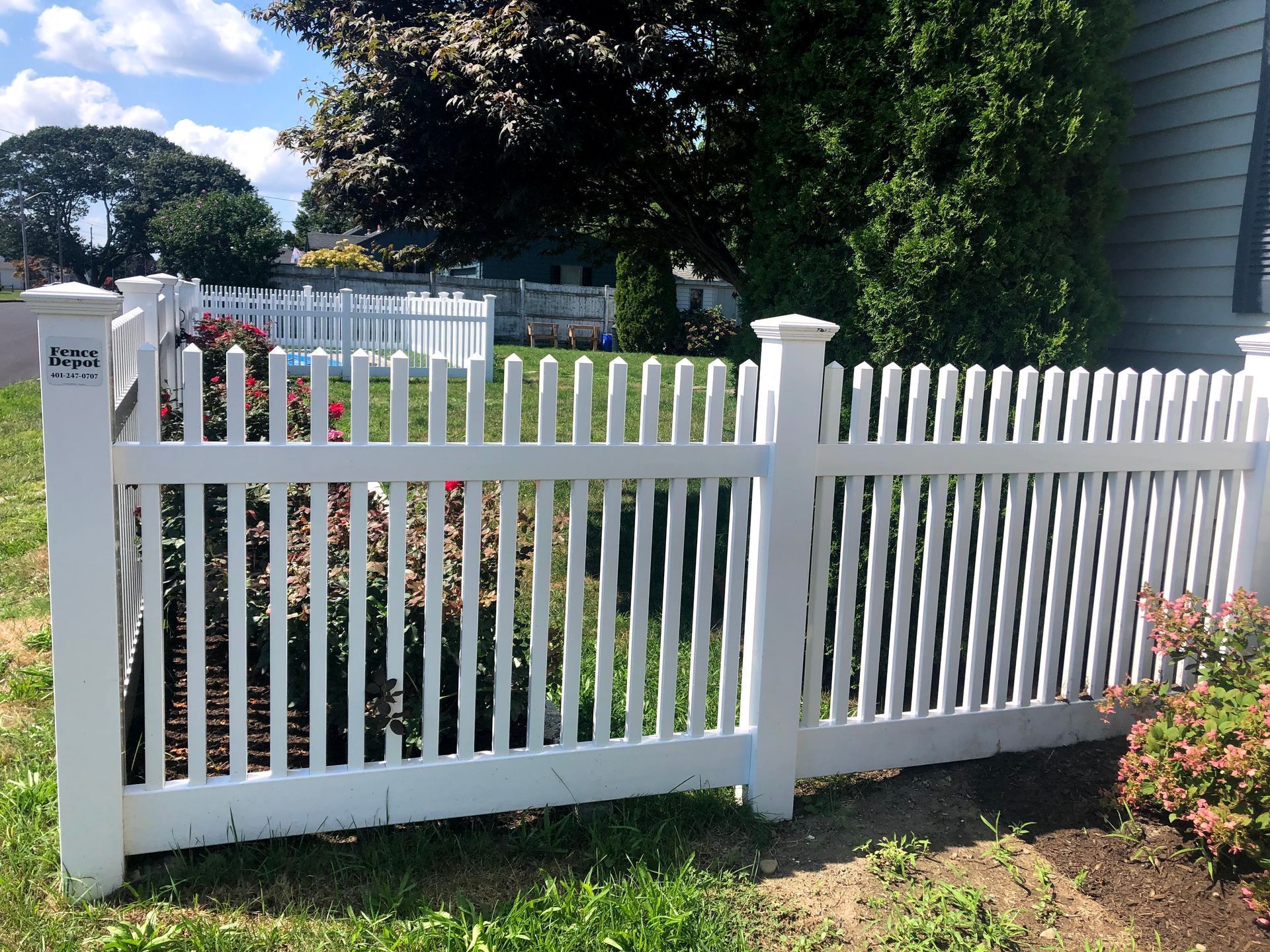 A white picket fence is in front of a house