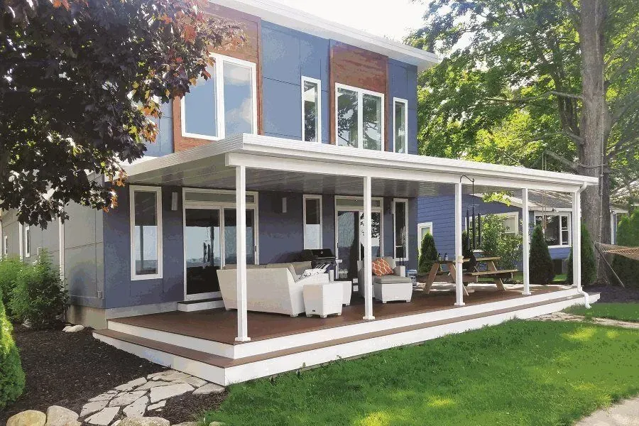 Two-story house with a blue exterior and a large porch overlooking a green lawn.