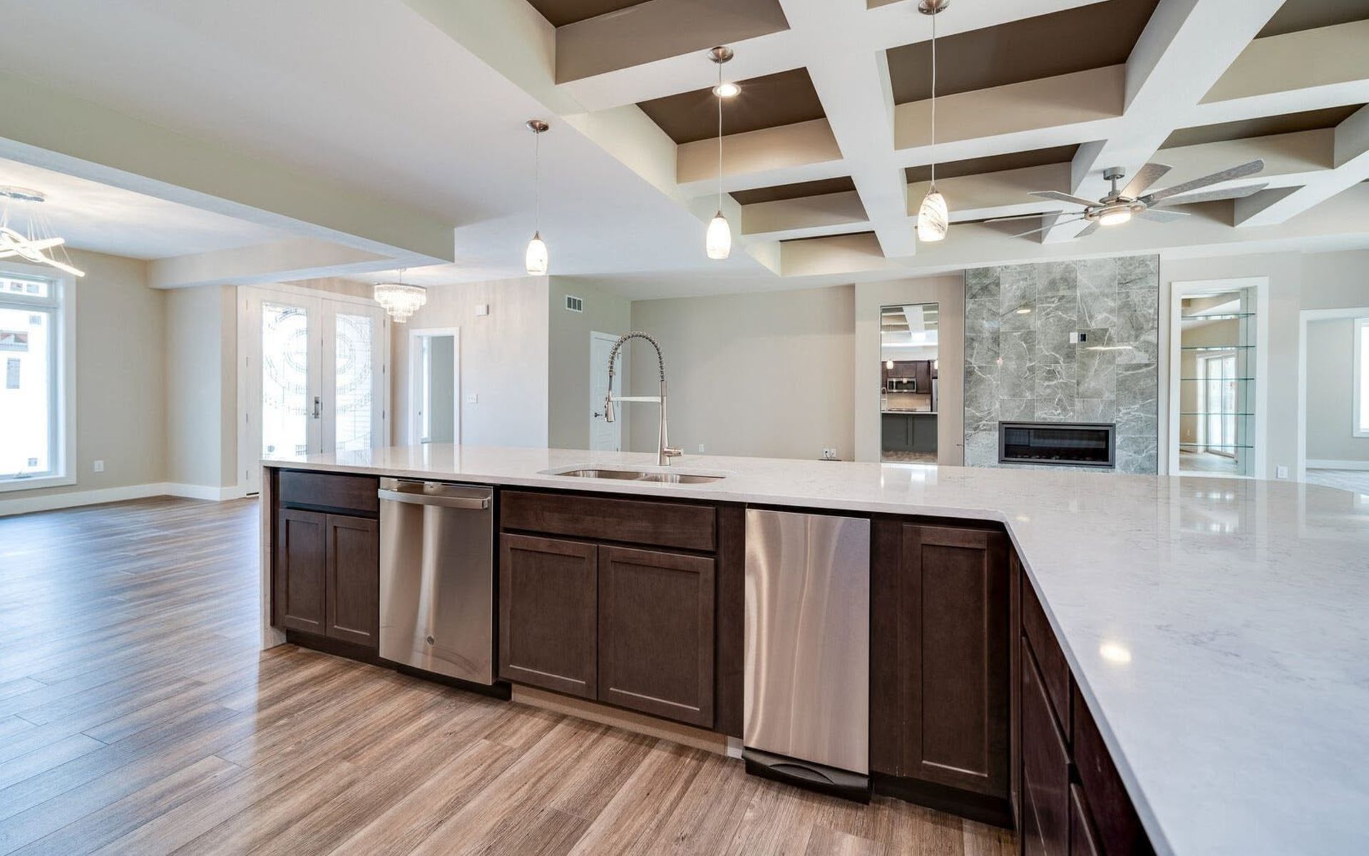 Modern open-concept kitchen with dark cabinets, white island, and coffered ceiling in a bright home.