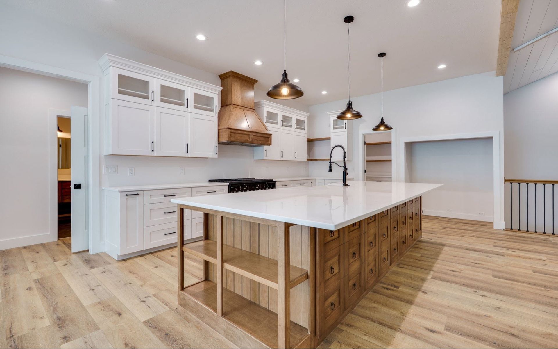 Bright modern kitchen with white cabinets, wood island, pendant lights, and light hardwood floors
