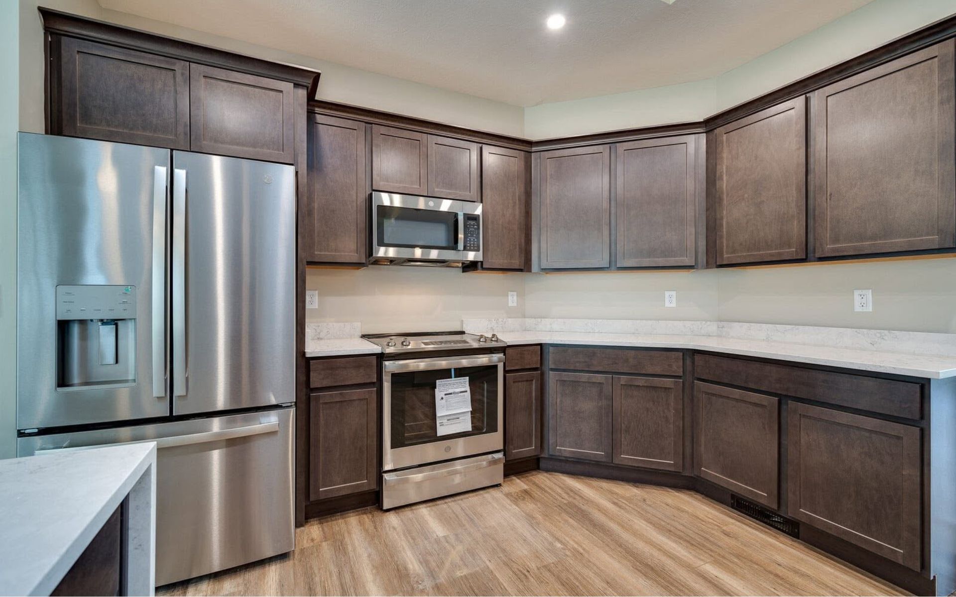 Modern kitchen with stainless steel appliances, dark wood cabinets, and light countertops