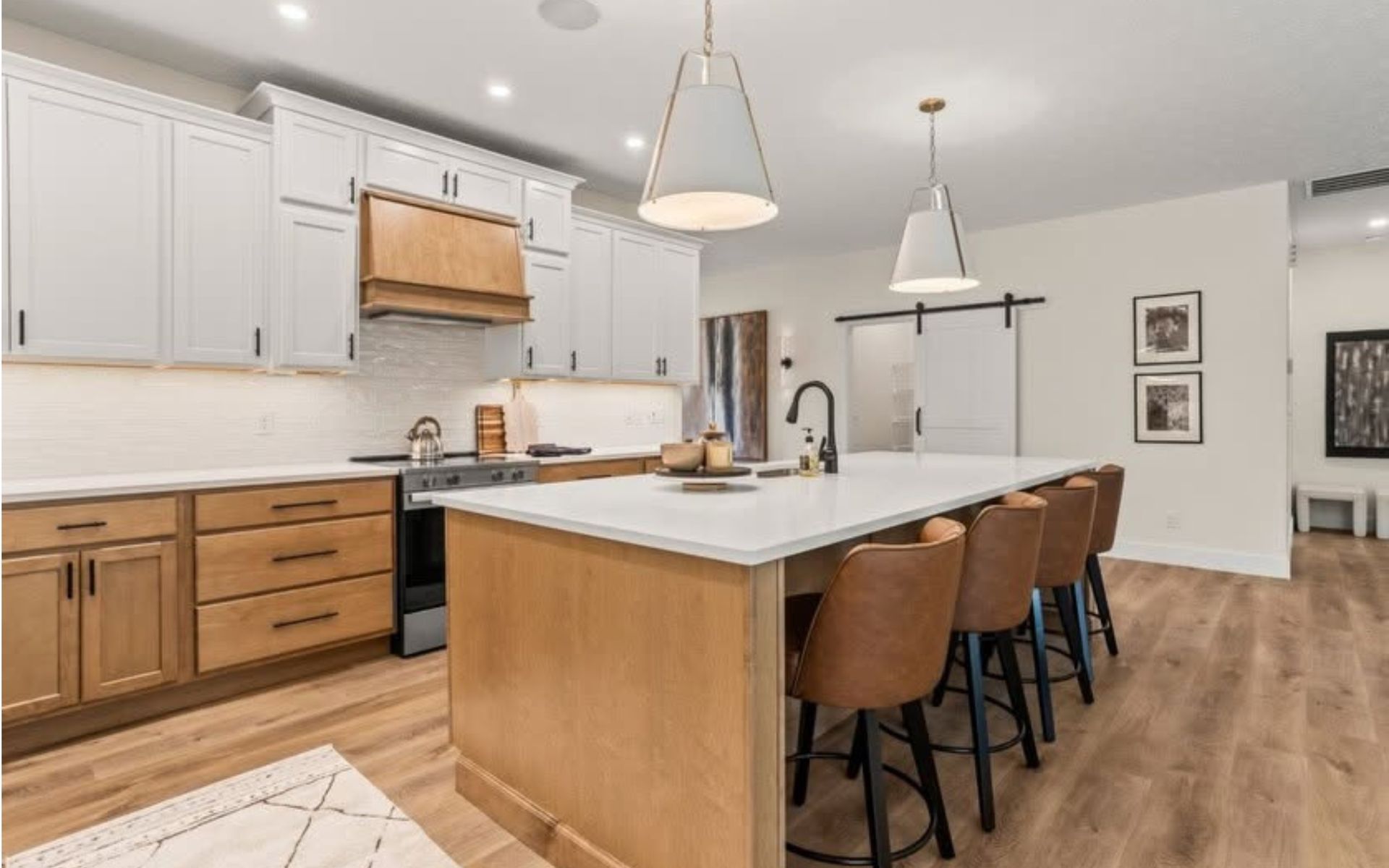 Modern kitchen with white cabinets, wood island, bar stools, and pendant lights