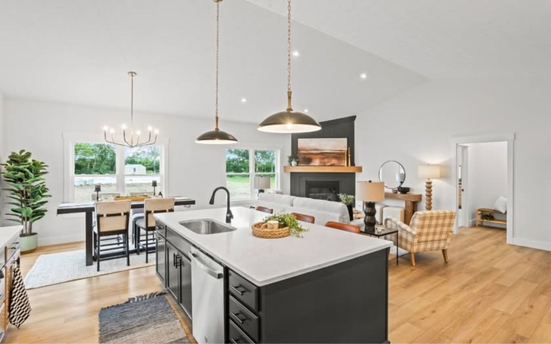 Modern open-plan kitchen with island, pendant lights, dining area, and living room in the background
