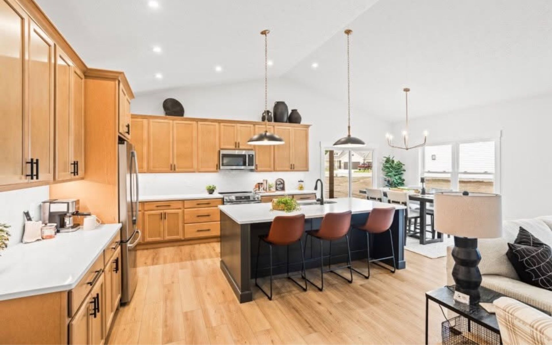 Bright modern kitchen with wood cabinets, white countertops, island seating, and pendant lights