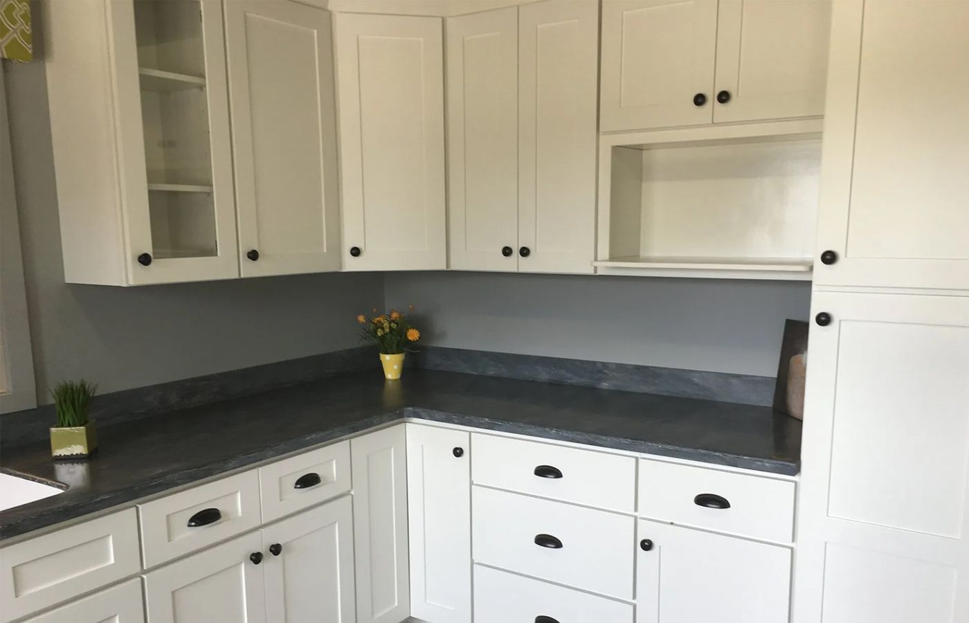 A kitchen with white cabinets and granite counter tops.