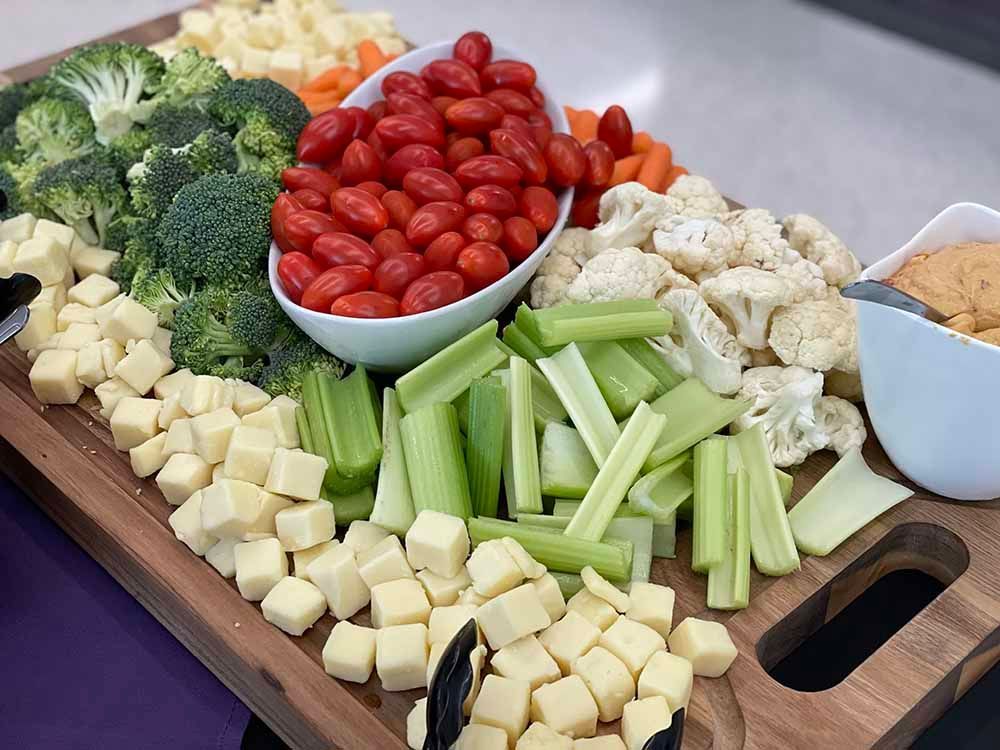 a wooden cutting board filled with vegetables and cheese