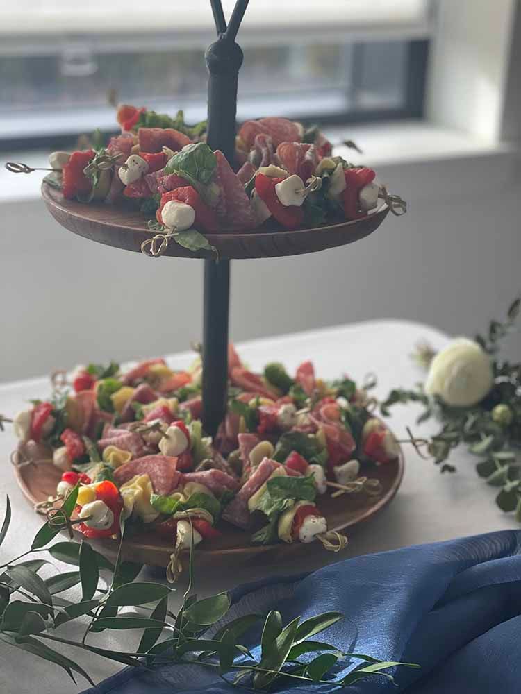 a three tiered tray filled with skewers of food on a table