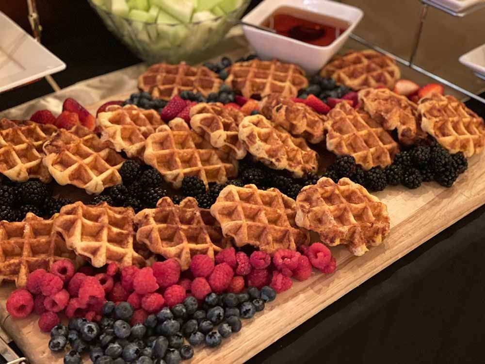 a wooden cutting board topped with waffles and berries