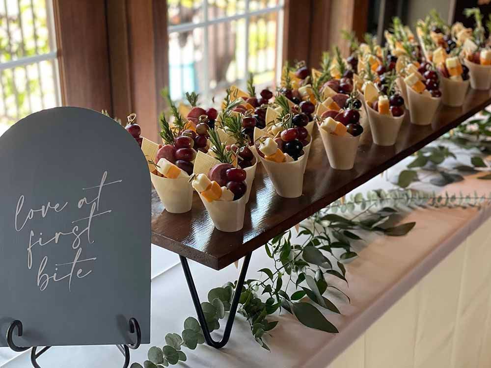 a wooden table topped with fruit cups and a sign