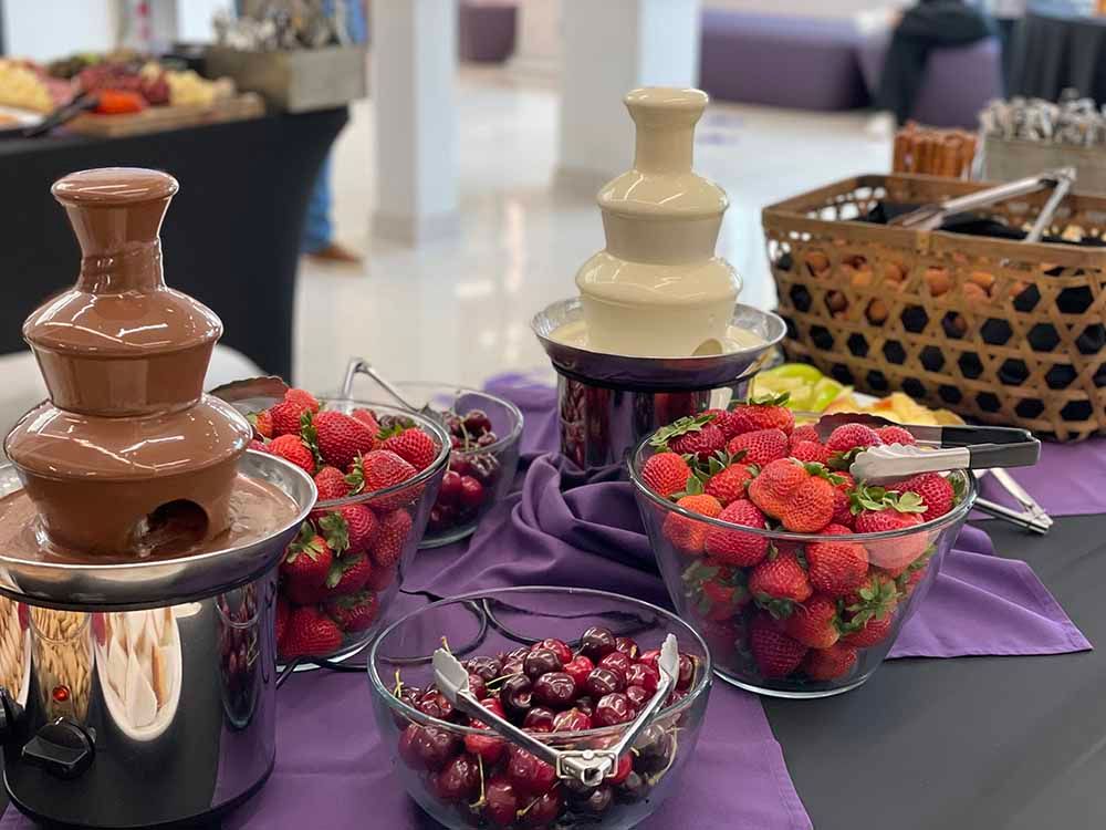 a table topped with bowls of fruit and chocolate fountains