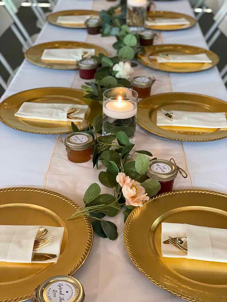 a table set for a wedding reception with gold plates , napkins , candles and flowers