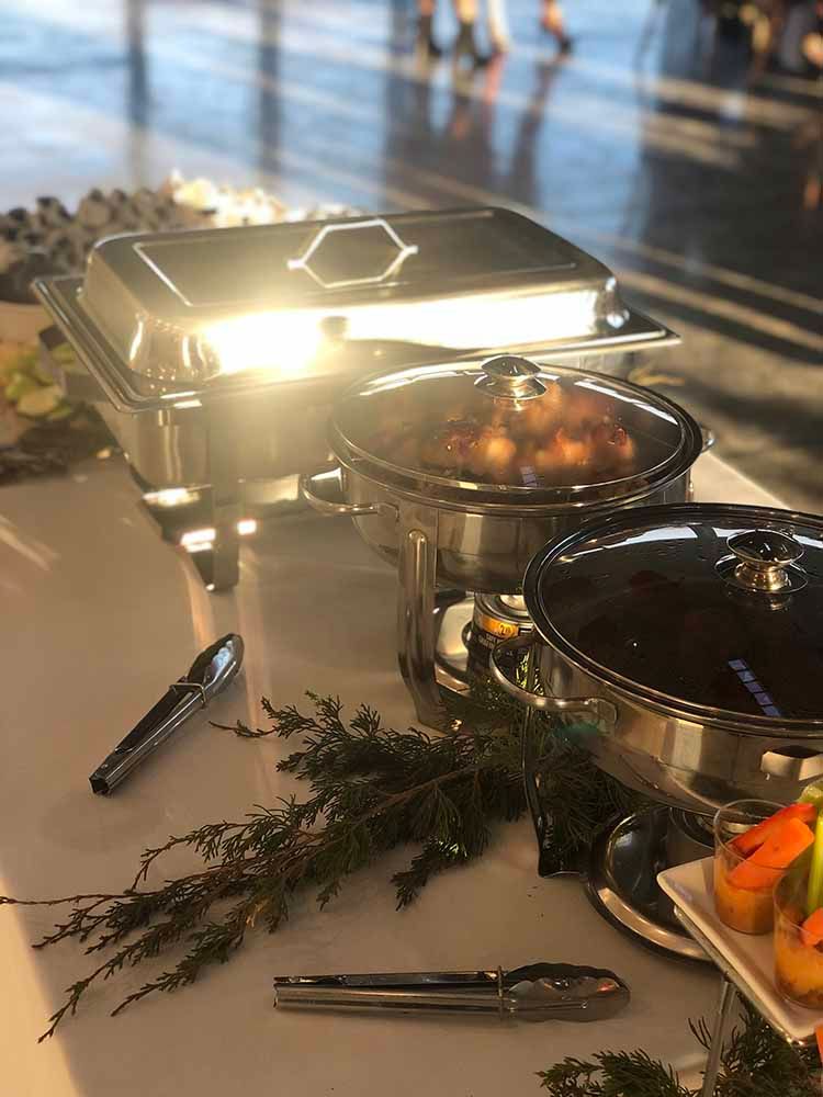 a buffet table with plates of food and tongs on it