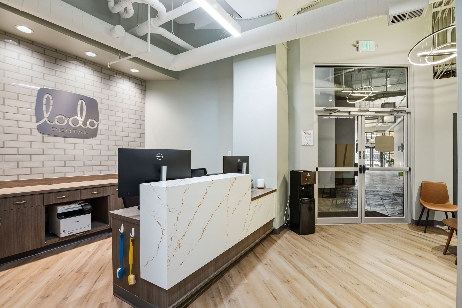 Reception area with a white marble desk, brick wall, and waiting area.