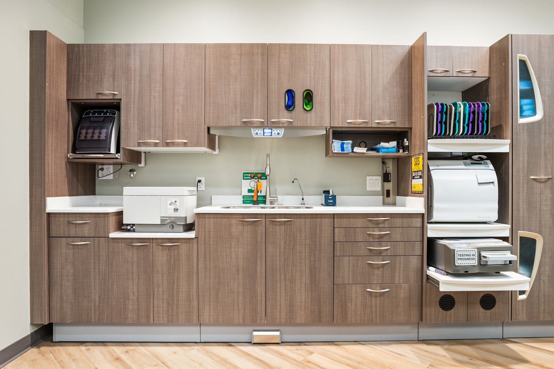 Dental office sterilization room with wood cabinets, white countertops, and sterilization equipment.