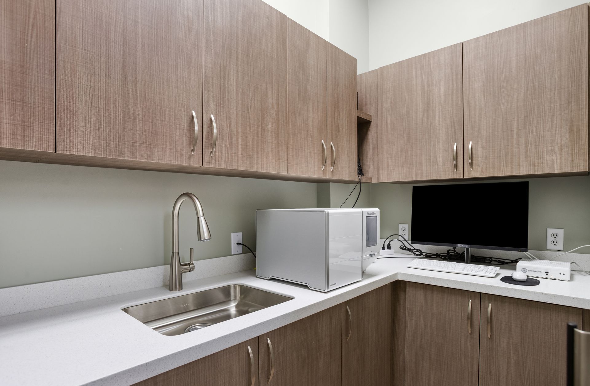 Dental office with wooden cabinets, a sink, and a computer.