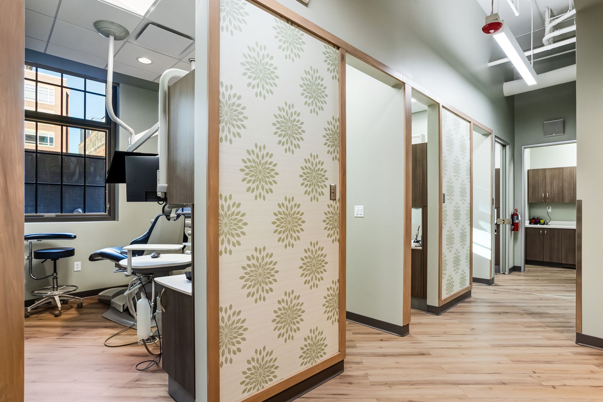 Dental office hallway with treatment rooms. Patterned sliding doors and wood floors.